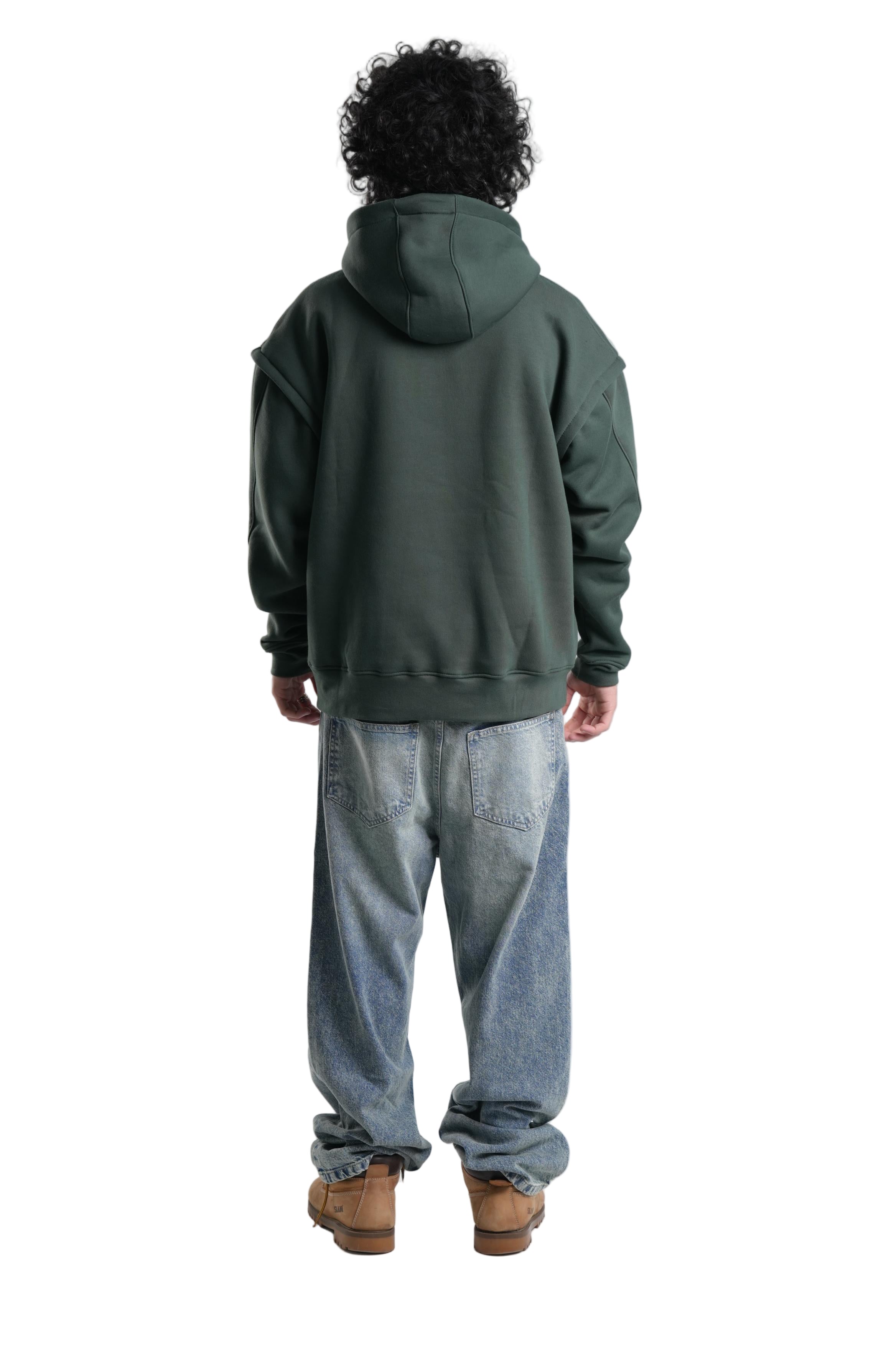 Person wearing a green hoodie and light blue jeans on a white background